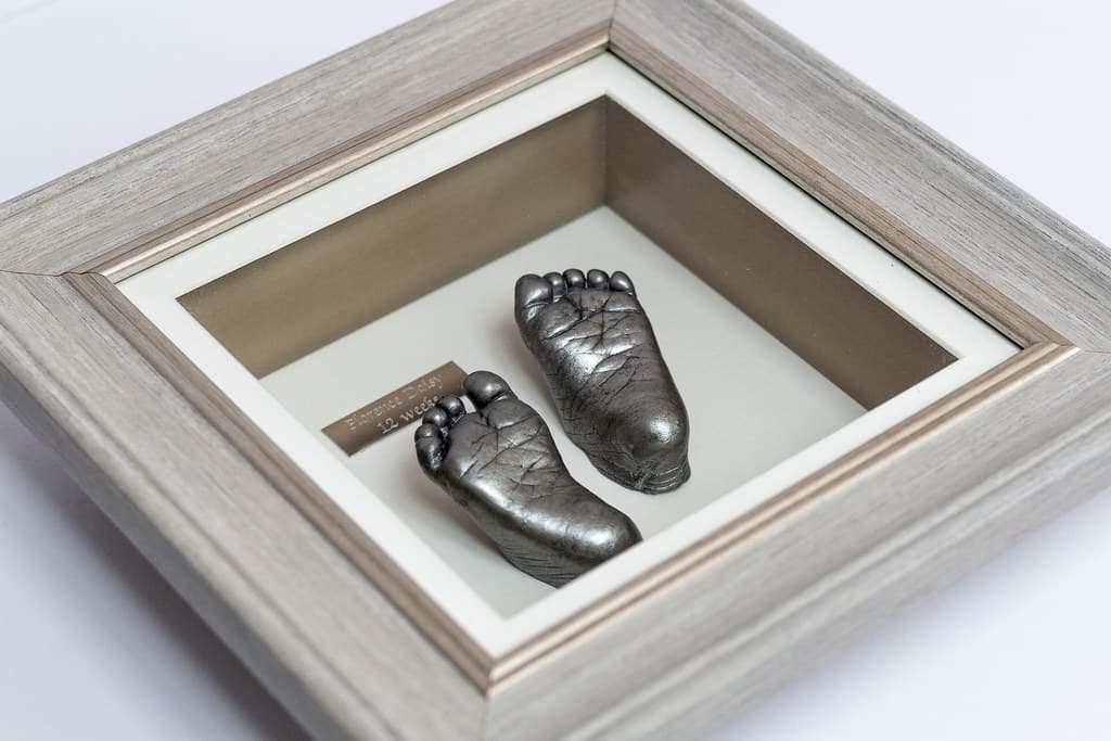 Bronze baby foot casting beside a photograph